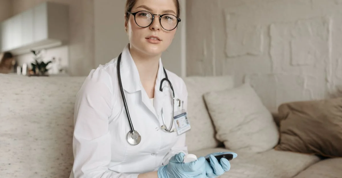 Doctora con glucómetro en un sofá, evaluando el control de azúcar en sangre en interiores.