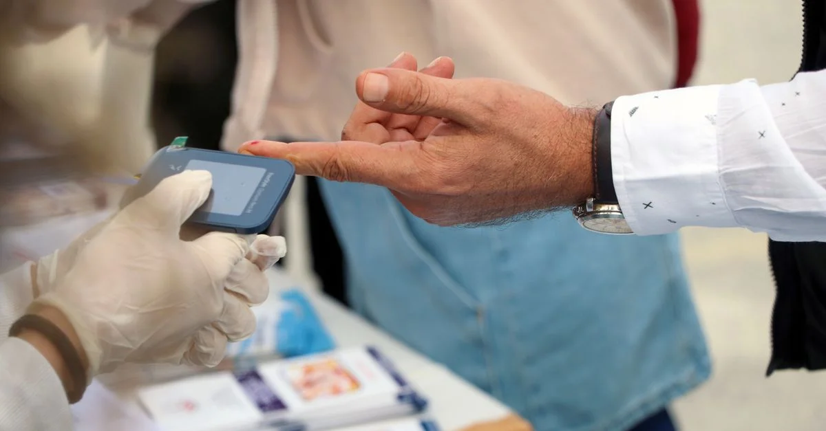 Un profesional sanitario controla el nivel de glucosa en sangre en un evento público.